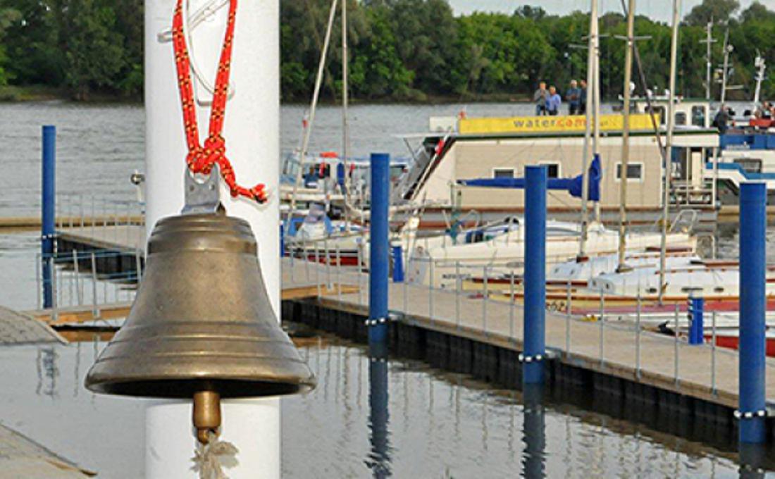 Zdjęcie przedstawia przystań z dzwonem marynarskim na pierwszym planie