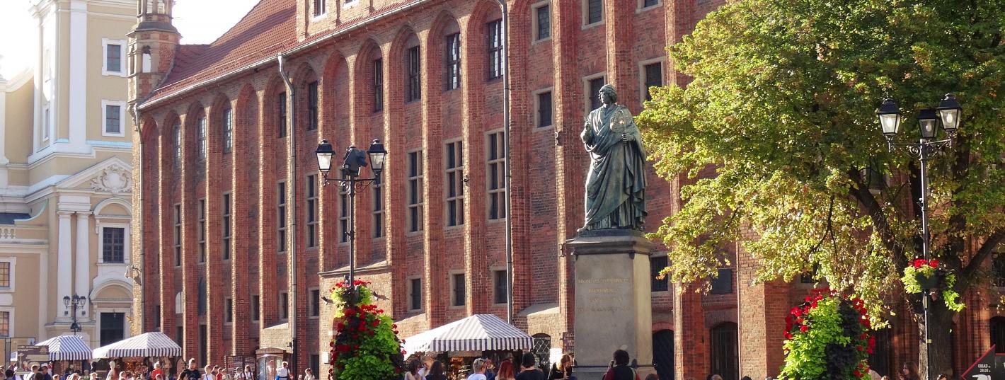 Ludzie spacerujący obok pomnika Mikołaja Kopernika